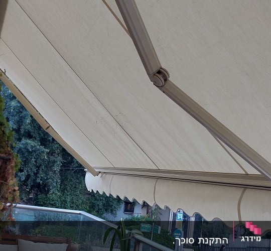 סוכך בד בהיר עם זרועות מתכת על מרפסת